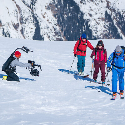 Kamerateam filmt drei Skitourengeher im Schnee für professionelle Luftaufnahmen und Videoprojekte