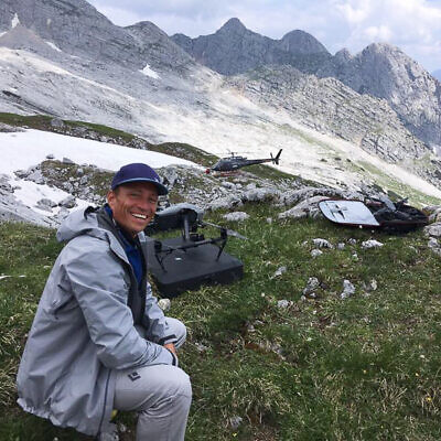 Mann mit Drohne in den Alpen, Ausrüstung für professionelle Luftaufnahmen und Videoproduktion