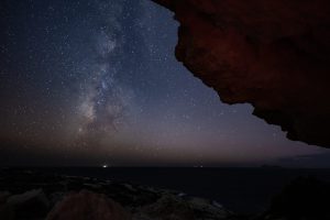 Sternenklare Nacht mit Milchstraße über Küste, Felsen im Vordergrund, Zeitraffer-Luftbild