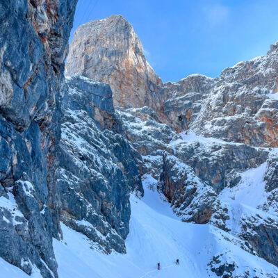 Zwei Bergsteiger gehen durch verschneites Hochgebirge, beeindruckende Luftaufnahme der Felsen